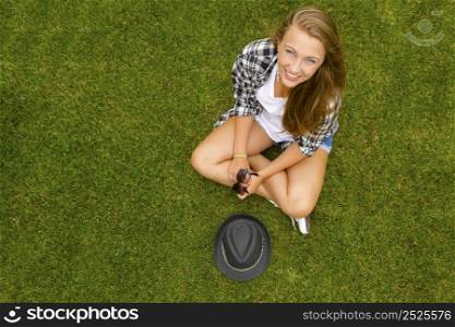 Happy and beautiful teenage girl sitting on the grass