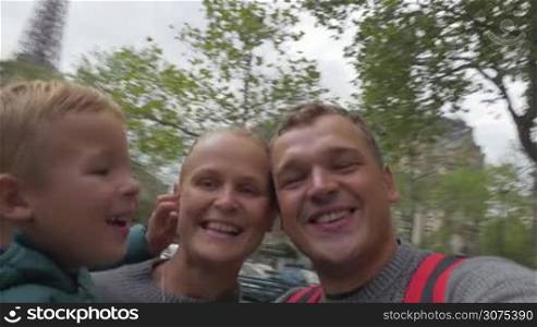 Happy and excited parents with little son shooting selfie on background of Eiffel Tower. Traveling to Paris, France