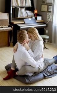 Happy and loving young couple kissing while sitting on the floor in the room