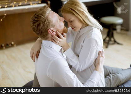 Happy and loving young couple kissing while sitting on the floor in the room