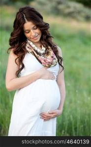 Happy and relaxed pregnant woman sitting on the grass