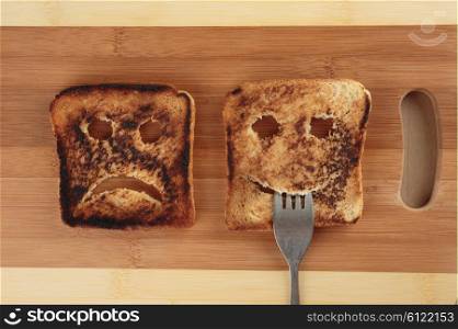 Happy and sad toast on a wooden cutting board