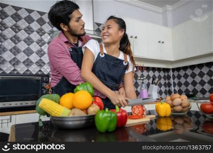 Happy and Smiling young couple cooking food in the kitchen at home
