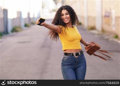 Happy Arab woman wearing casual clothes with open arms in the street.. Happy Arab woman with open arms in the street.