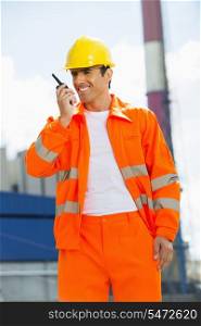 Happy architect wearing reflective workwear communicating on walkie-talkie at site