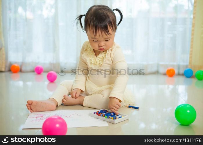 Happy asian baby girl painting with colors in house