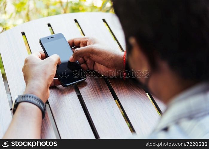 Happy Asian black businessman person holding a modern digital smart phone blank screen device technology and connecting networking online at the coffee cafe shop