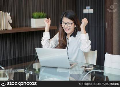 Happy Asian business woman finishing works in office