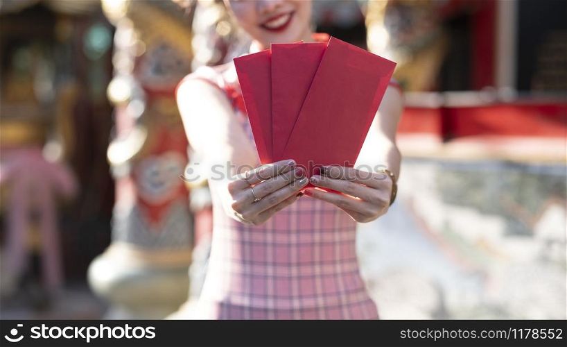 Happy Asian Chinese woman holding red envelope for giving ang pao in Chinese Lunar New Year. Happy Chinese new year concept.