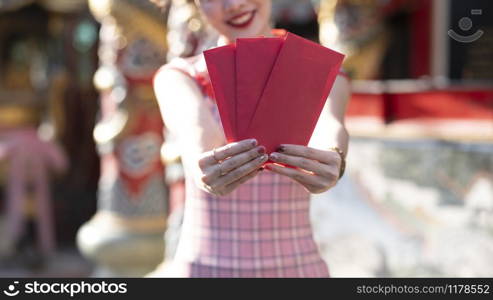 Happy Asian Chinese woman holding red envelope for giving ang pao in Chinese Lunar New Year. Happy Chinese new year concept.