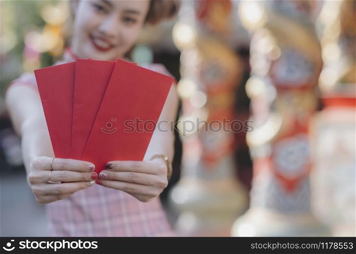 Happy Asian Chinese woman holding red envelope for giving ang pao in Chinese Lunar New Year. Happy Chinese new year concept.