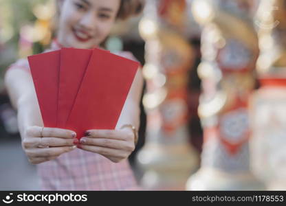 Happy Asian Chinese woman holding red envelope for giving ang pao in Chinese Lunar New Year. Happy Chinese new year concept.