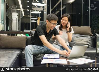 Happy Asian couple are working together and calling at night