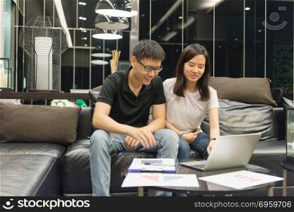 Happy Asian couple are working together at night