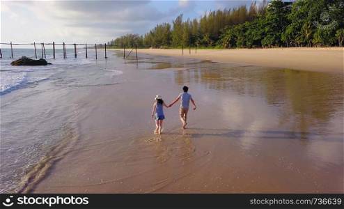Happy Asian couple dating at the beach during travel honeymoon trip on holidays vacation outdoors. Ocean or nature sea at sunset, Phuket, Thailand