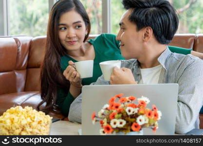 Happy Asian couple drink coffee at home. Love relationship and lifestyle concept.