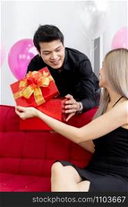 Happy asian couple opening New year present gift box togerther for season greeting.