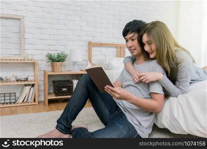 Happy Asian couple reading the book or notebook on the bed in the bedroom at modern home, Lover and life style concept
