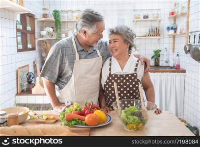 Happy asian elder senior couple cooking fresh meal in kitchen at home.