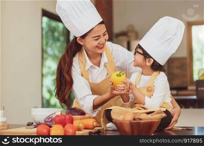 Happy Asian family in kitchen. Mother and son in chef hat preparing food in home kitchen together. People lifestyle and Family. Homemade food and ingredients concept. Two Thai people in teaching class