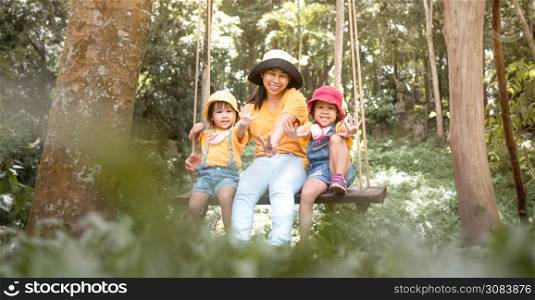 Happy asian family playing swing outdoor in the park on summer time.