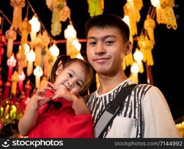 Happy Asian family standing over light from Thai lanna lanterns background at night in Yi Peng Festival.