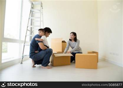 Happy Asian family with cardboard boxes in new house at moving day, Real estate and home concept