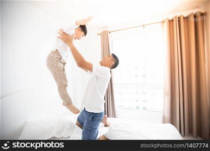 Happy Asian family with son at home on the bedroom playing and laughing