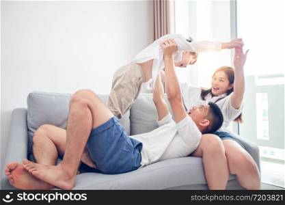 Happy Asian family with son at home on the sofa playing and laughing