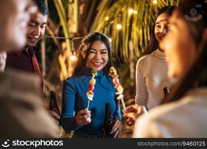 Happy Asian friends cheering with barbecue dinner outdoor - Group of people having fun in new year party. People, food and drink lifestyle concept Night Party, people and celebration concept.