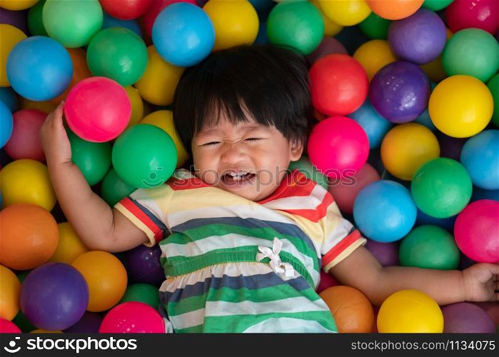 Happy Asian girl (one and half years olds) big smile and playing little colorful balls in pool ball. The concept of playing is the best learning for children.