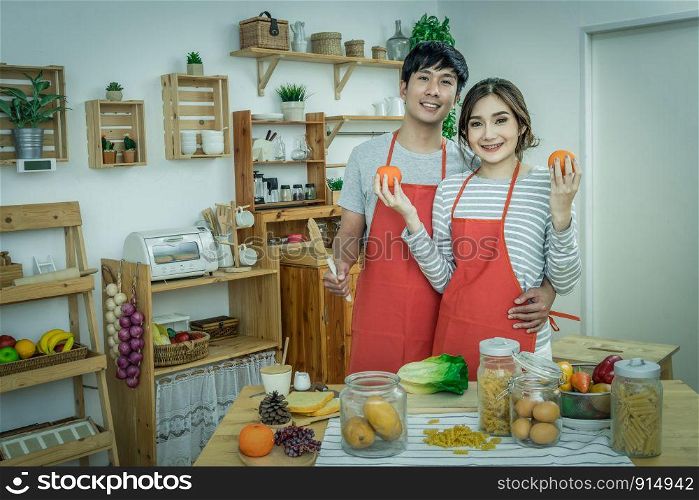 Happy Asian Lover or couple cooking in happiness action in the kitchen room at the modern house, Couple and life style concept.