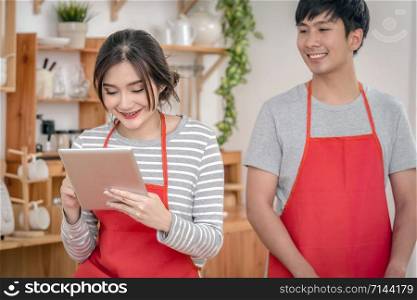 Happy Asian Lover or couple cooking in happiness action with technology tablet via social network in the kitchen room at the modern house, Couple and life style concept.