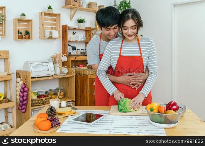 Happy Asian Lover or couple hugging and cooking in happiness action in the kitchen room at the modern house, Couple and life style concept.
