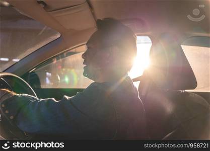 happy Asian man driving a car with sun ray in background