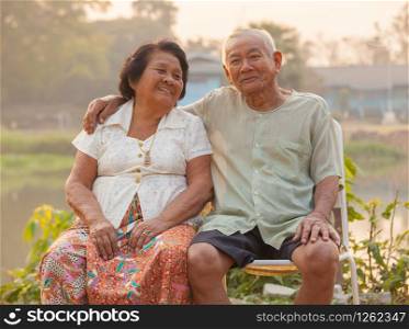 Happy Asian Senior couple sitting outdoors on sunset