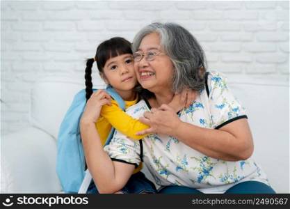 Happy Asian senior grandmother sit on a couch and  granddaughter