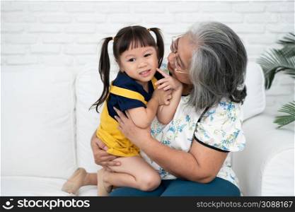Happy Asian senior grandmother sit on a couch and granddaughter