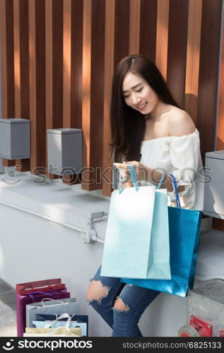 happy asian shopaholic woman with colorful shopping bags at department store shopping mall