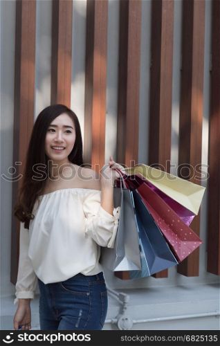 happy asian shopaholic woman with colorful shopping bags at department store shopping mall