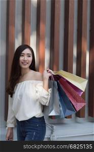 happy asian shopaholic woman with colorful shopping bags at department store shopping mall