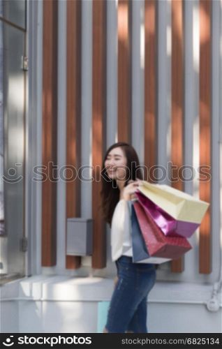 happy asian shopaholic woman with colorful shopping bags at department store shopping mall, blur background