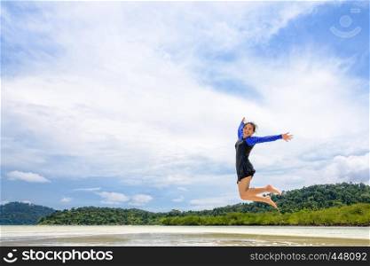 Happy asian teen girl in a swimsuit jumping fun on the beach of Ko Ra Wi on blue sky background during the sea tour vacation in summer holiday at Ko Lipe island, Tarutao National Park, Satun, Thailand. Happy asian teen girl jumping fun on the beach