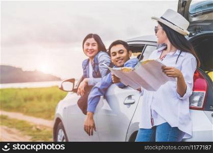 Happy Asian woman and her friends standing by car on coastal road at sunset. Young girl having fun during road trip. People lifestyles and travel vacation concept. Friendship journey and Outdoor tour