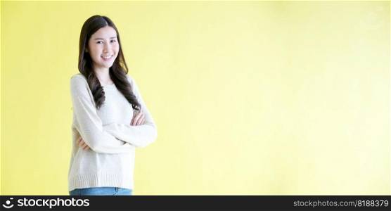 Happy asian woman arm cross, smiling and looking at camera while standing over isolated yellow background with copy space, Portrait of asia female 