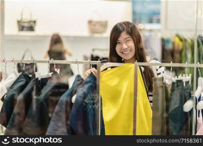 Happy Asian woman choosing clothes and skirt in glass store shop with happy action at department center