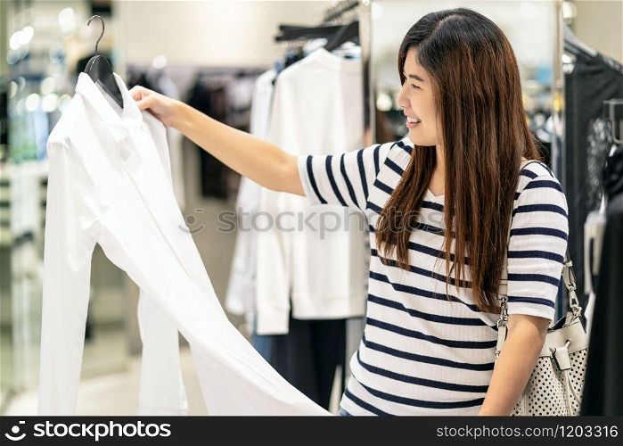 Happy Asian woman choosing clothes in glass store shop with happy action at department center