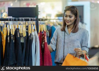 Happy Asian woman choosing clothes in shop store with happy action at department center