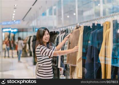 Happy Asian woman choosing clothes in store shop with happy action at department center