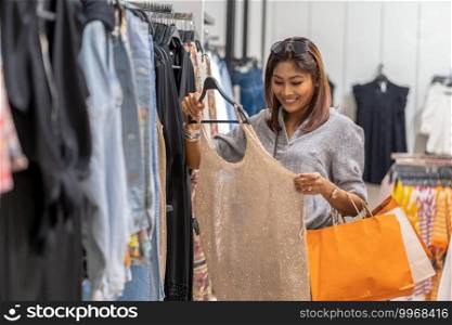 Happy Asian woman choosing clothes with in store shop with happy action at department center